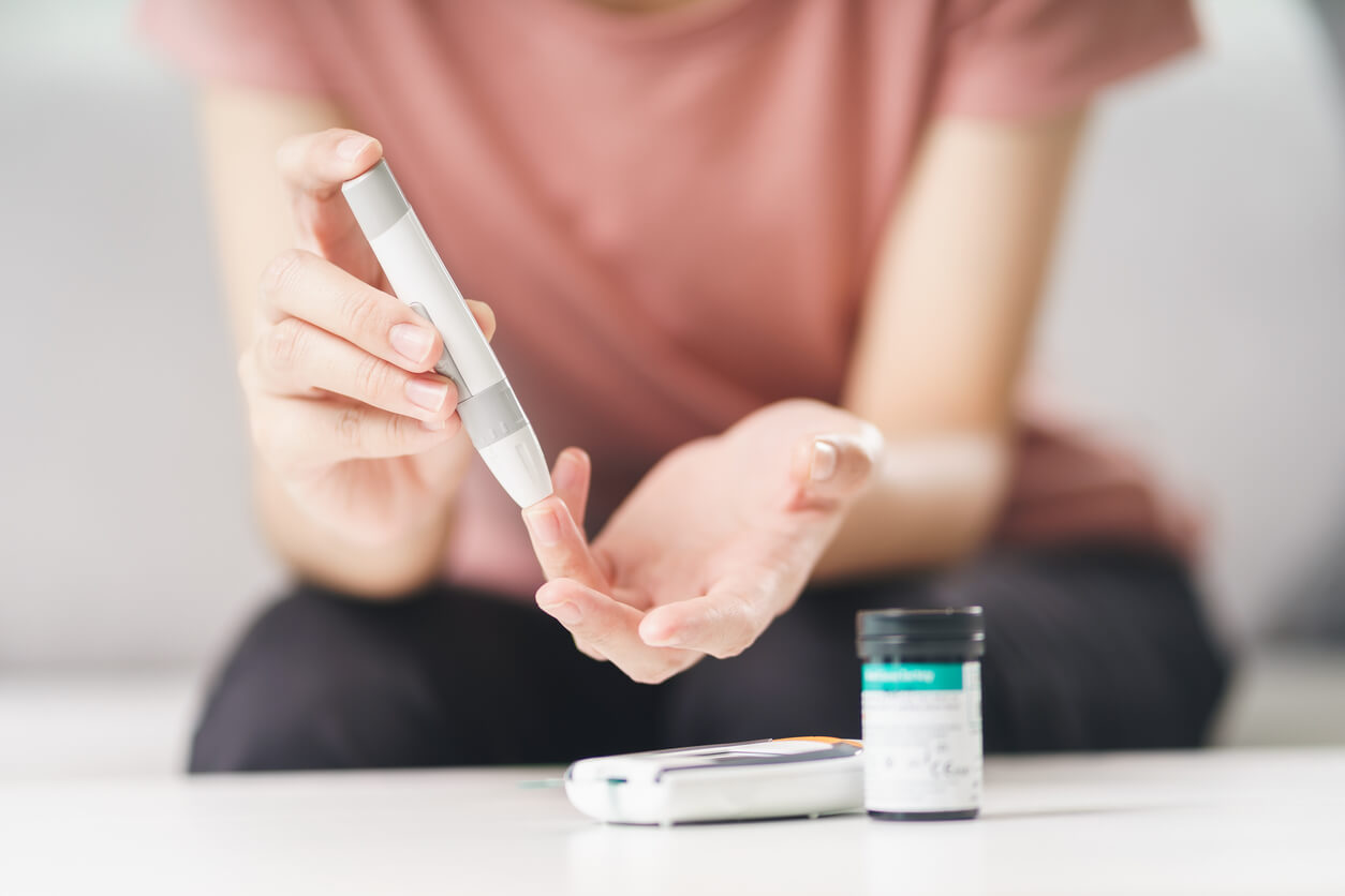 woman using lancet on finger for checking blood sugar level by Glucose meter