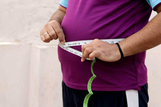 torso of obese person with tape measure around the stomach area - obesity treatment concept