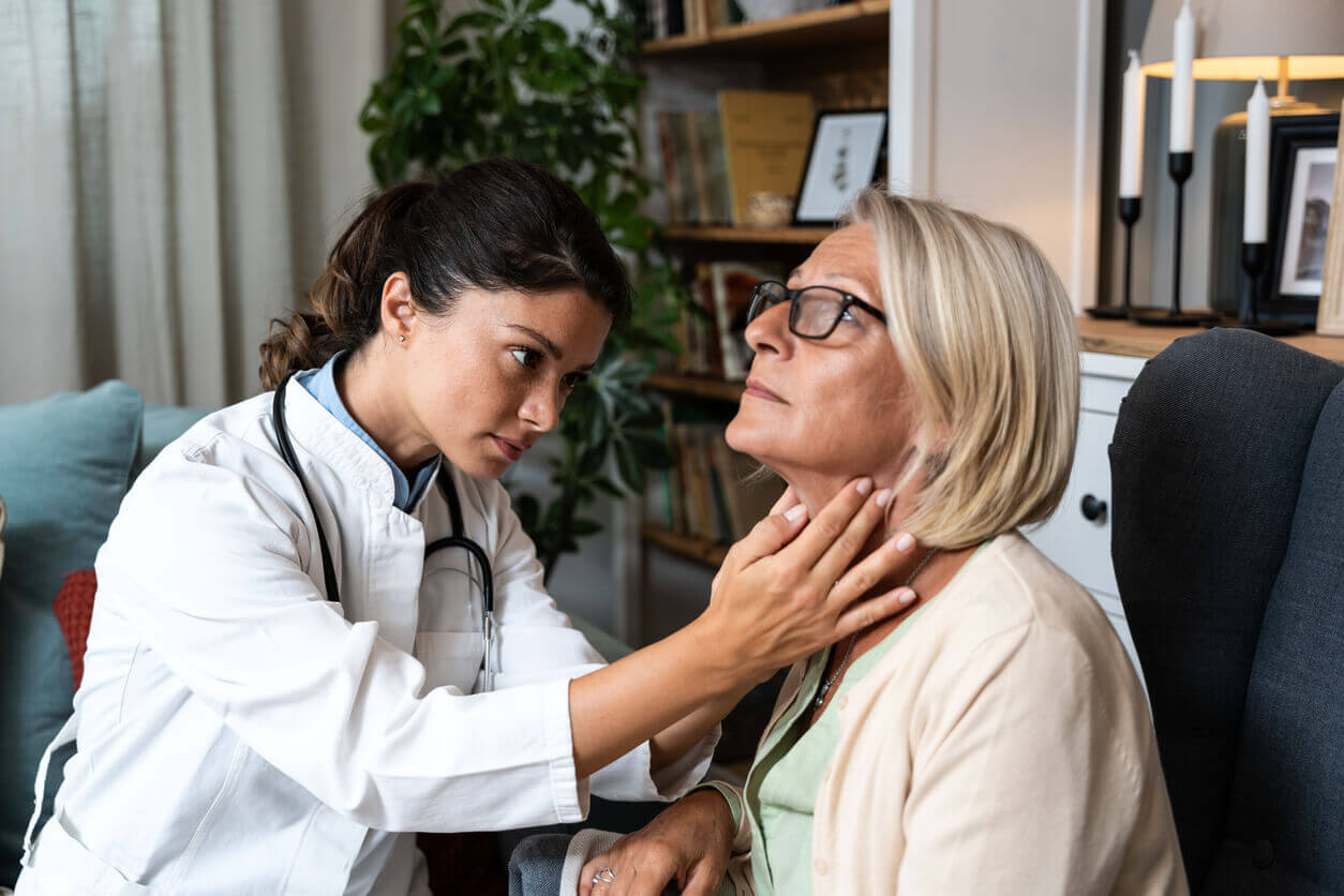 Image of a young female endocrinologist examining a senior woman’s thyroid gland by palpating her neck to check for hypothyroidism.