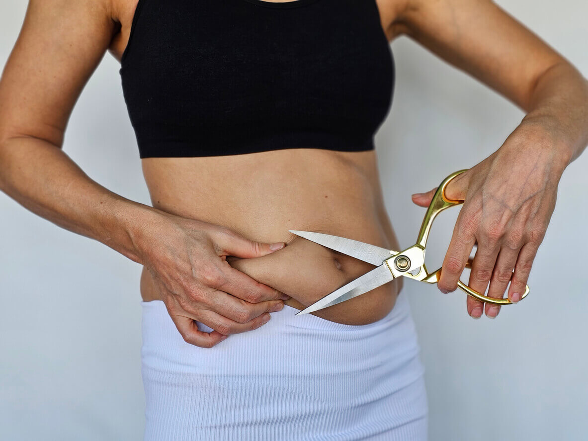 Image depicting a body part of an overweight woman with a measuring tape and scissors, representing the concepts of weight gain, obesity, and fat removal.