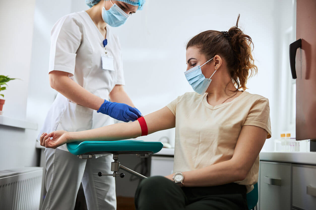 An experienced phlebotomist is preparing a woman for a blood draw as part of her physical examination.